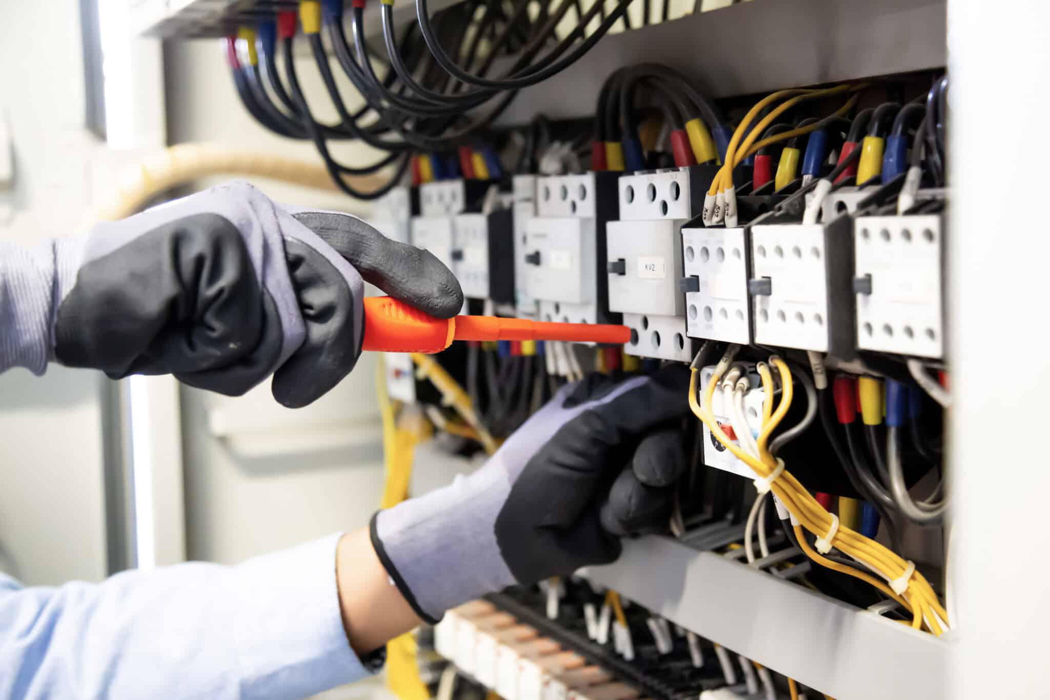 hands with gloves on working on electrical panel